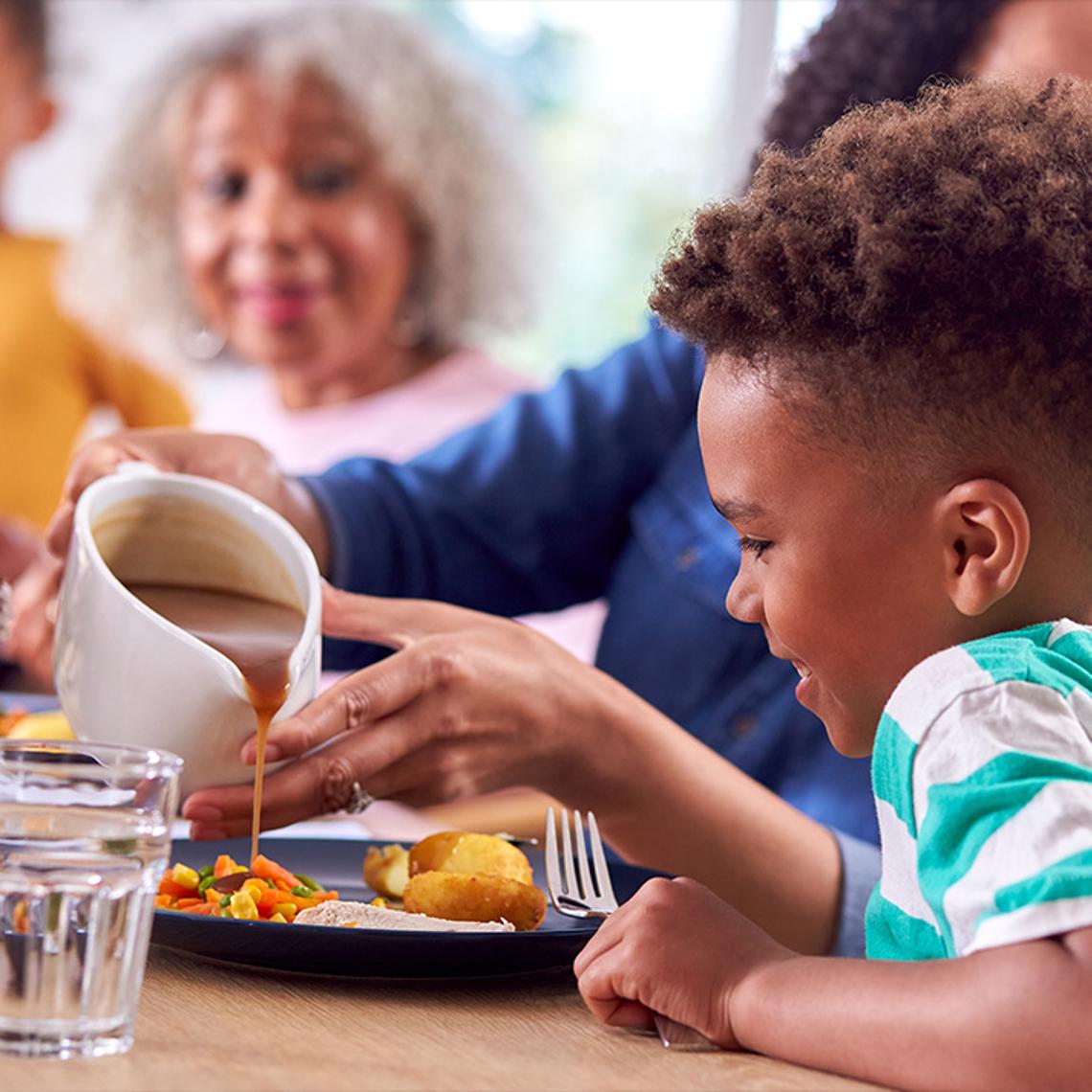 A child pouring gravy on his dinner