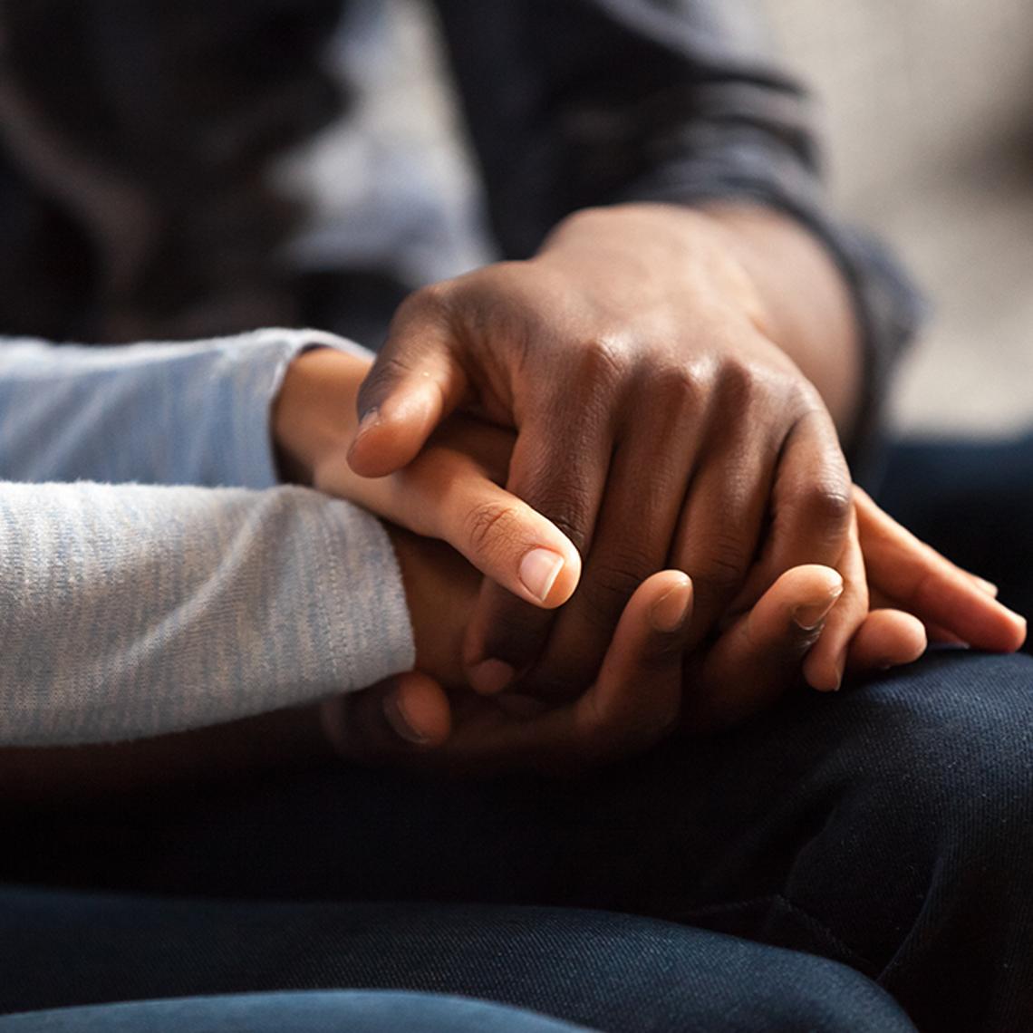 Two people holding hands in support 