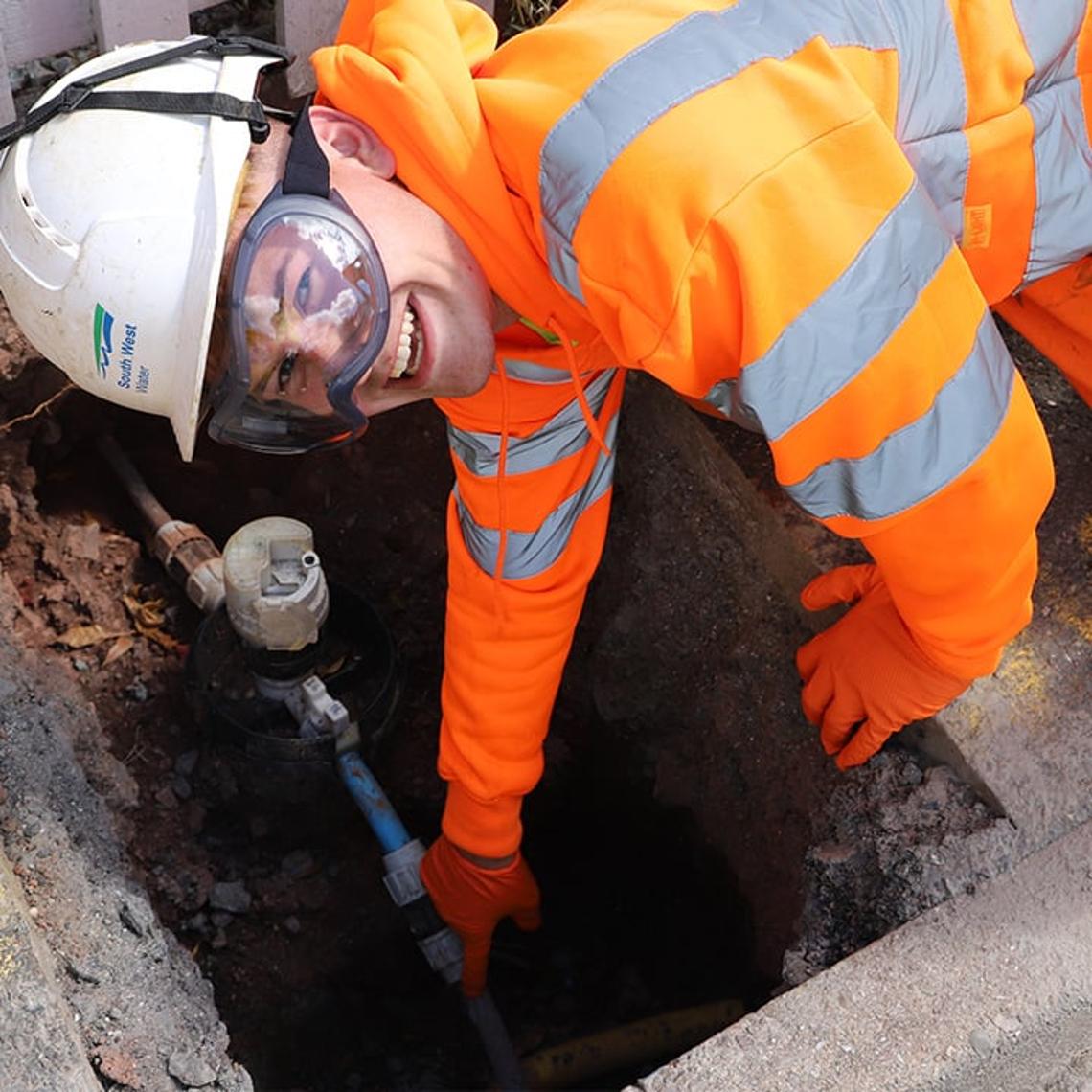 South West Water employee pointing at a lead pipe in the ground