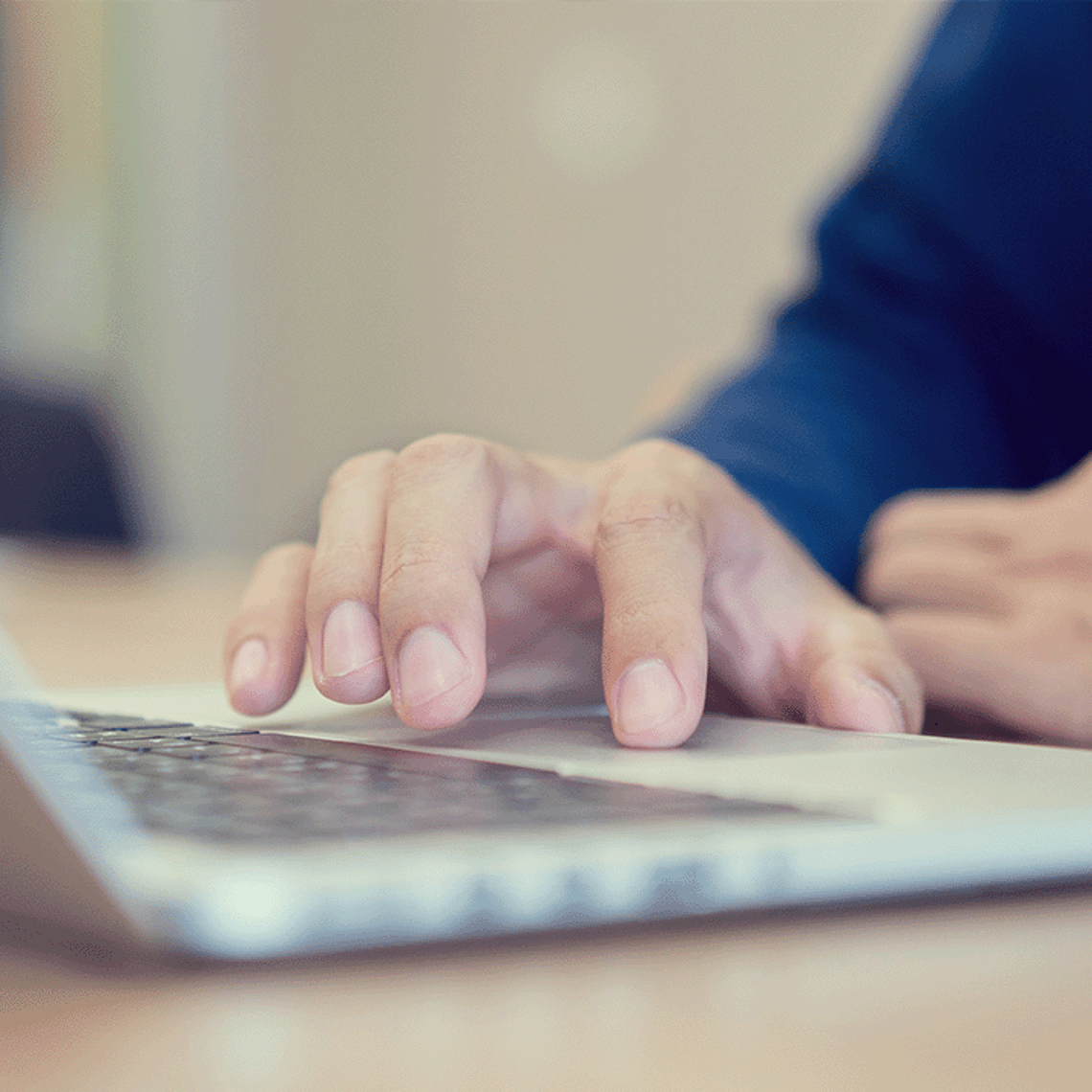 Close up of a hand using a laptop