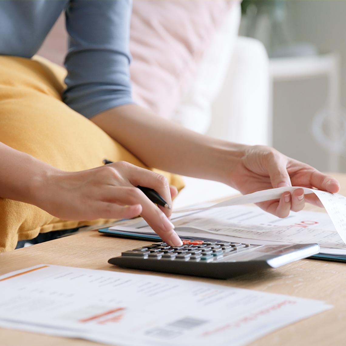 Lady looking at bills and using a calculator