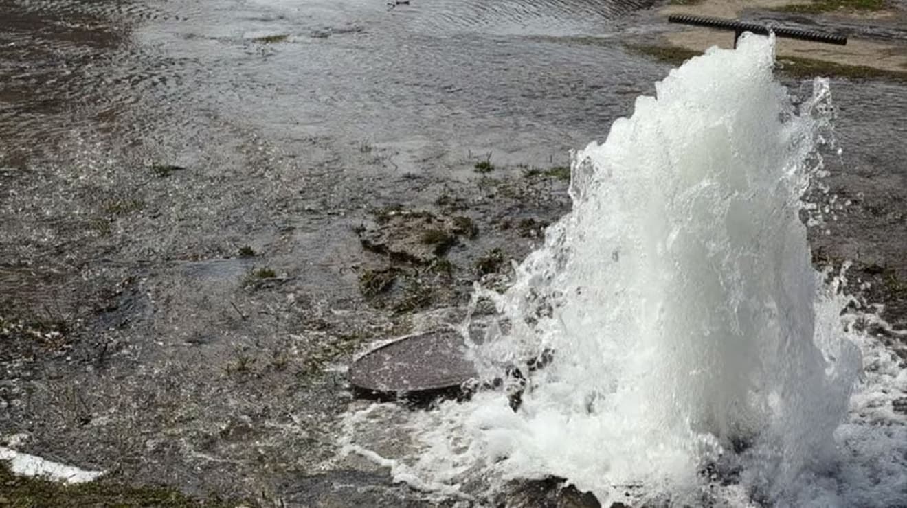 Water bursting from a main pipe under the road