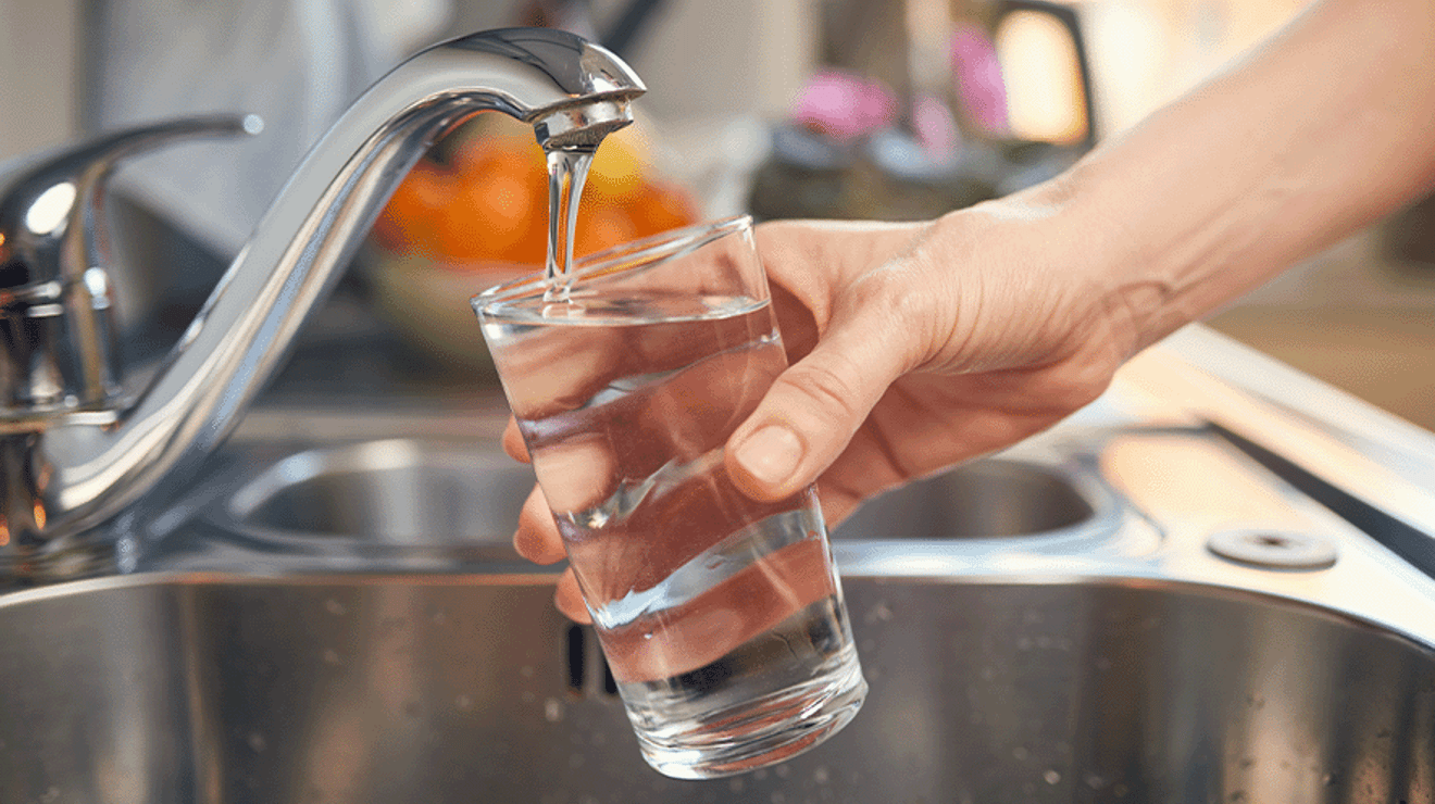 Hand holding a glass under a tap filling it with water