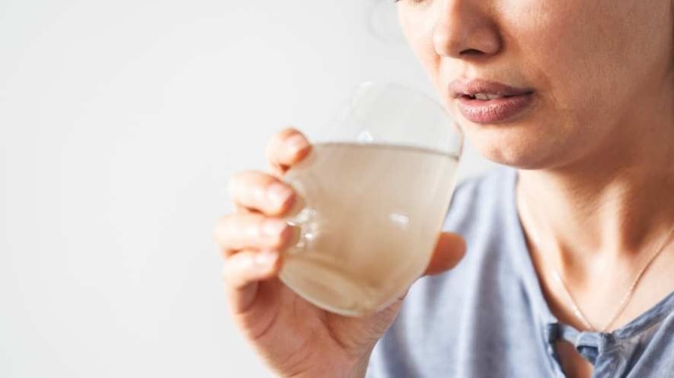 woman holding a glass of discoloured tap water