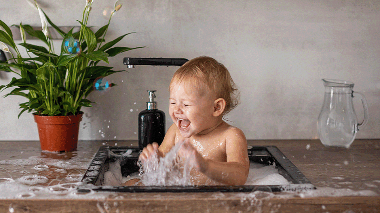 Baby having a wash in a sink