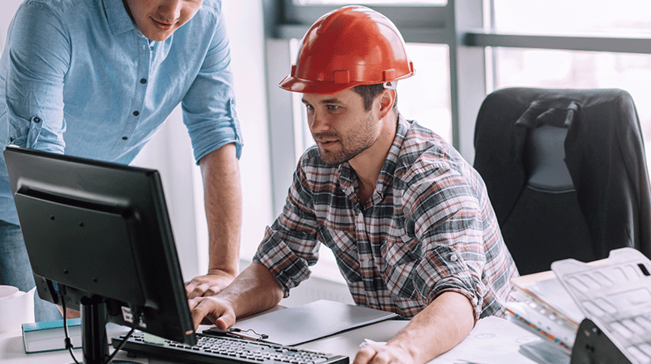 Builder in a red hard hat using a computer