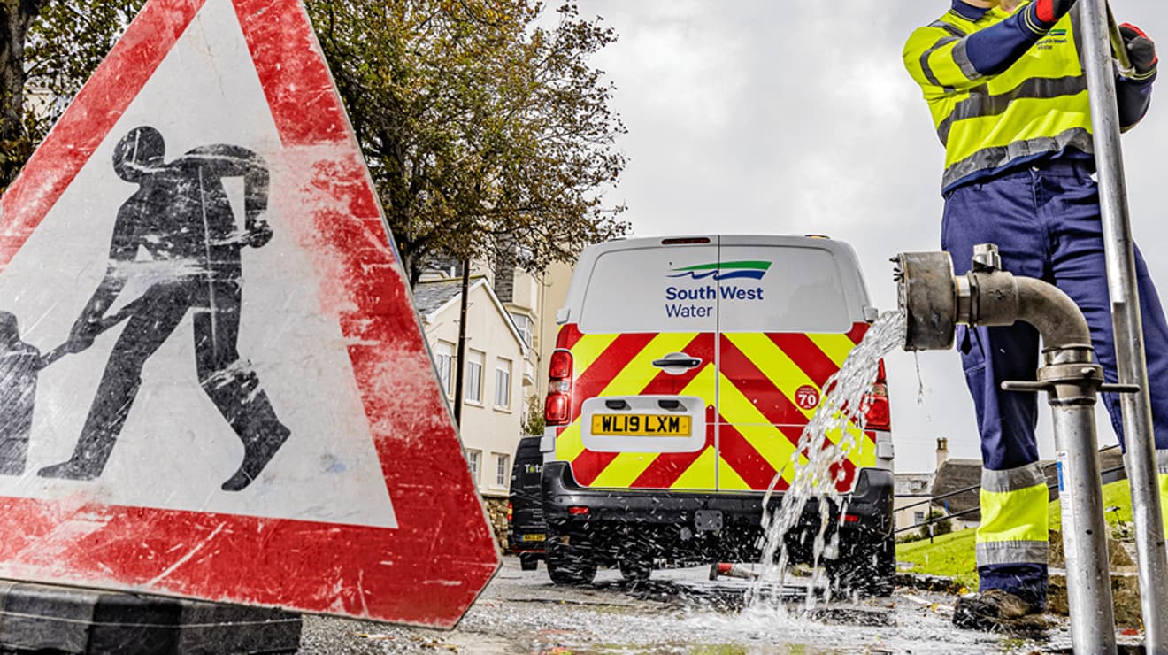 Worker flushing water in the street