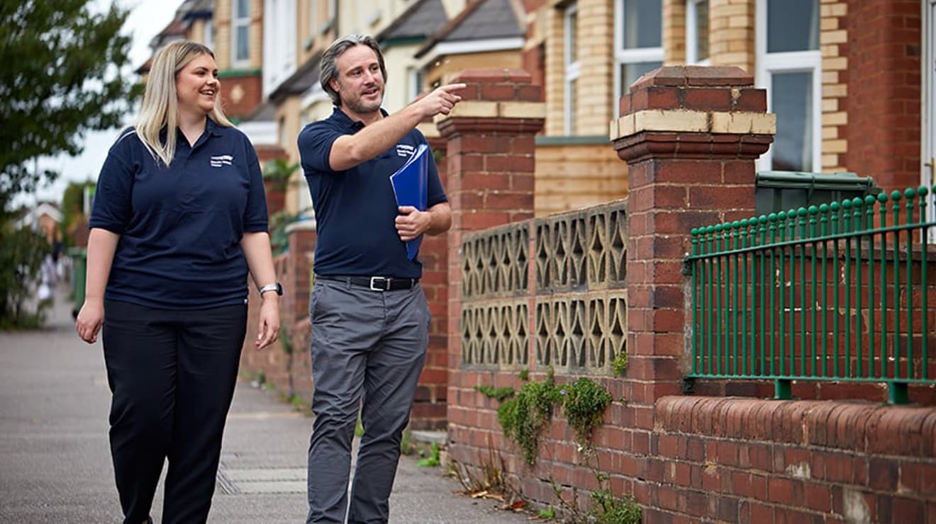 2 South West Water employees walking down a residential road smiling