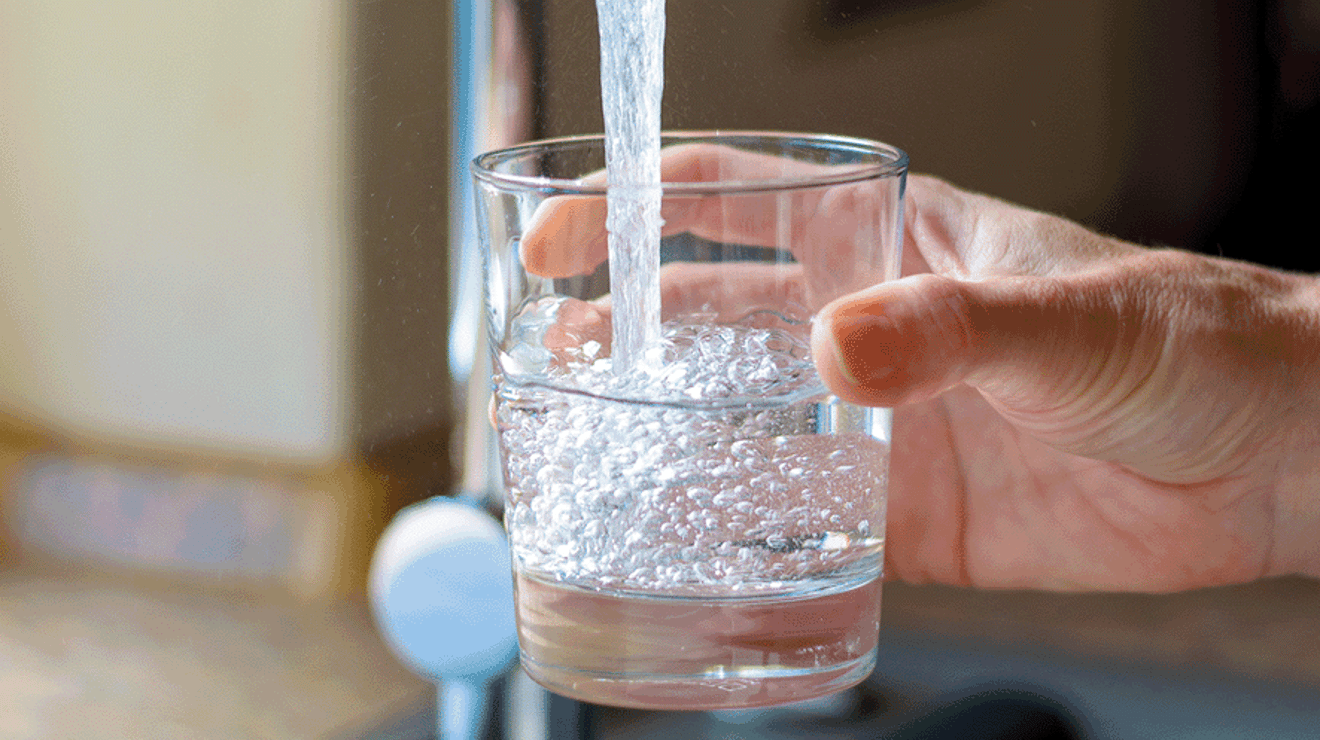 Glass under tap being filled with water