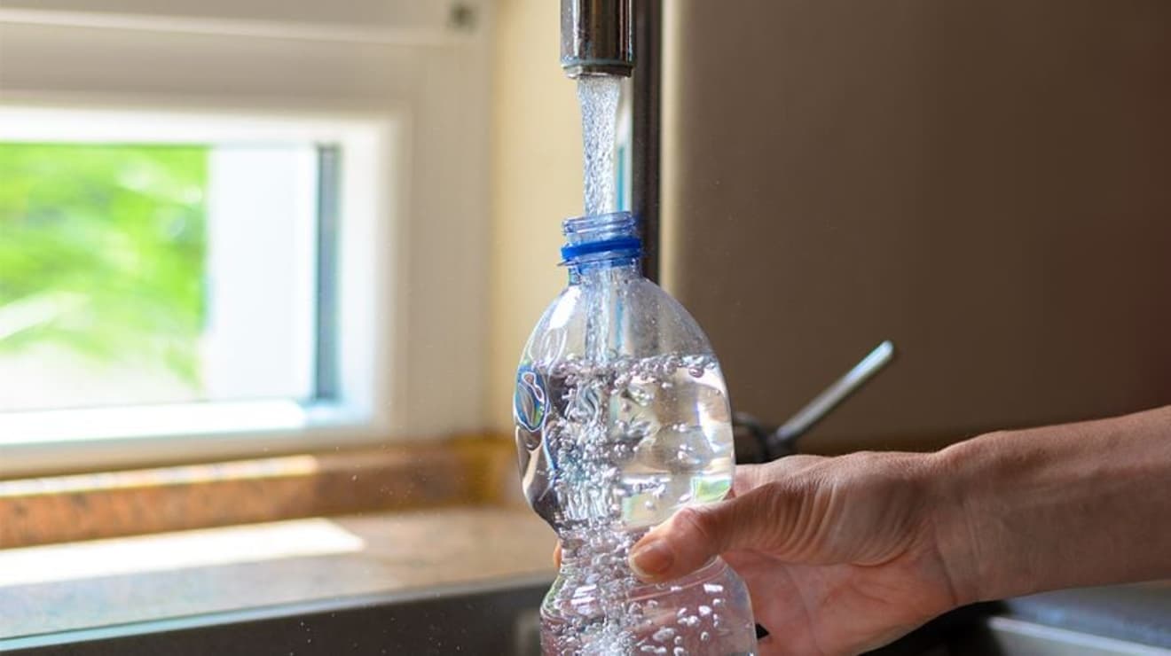 Plastic water bottle being filled by a tap