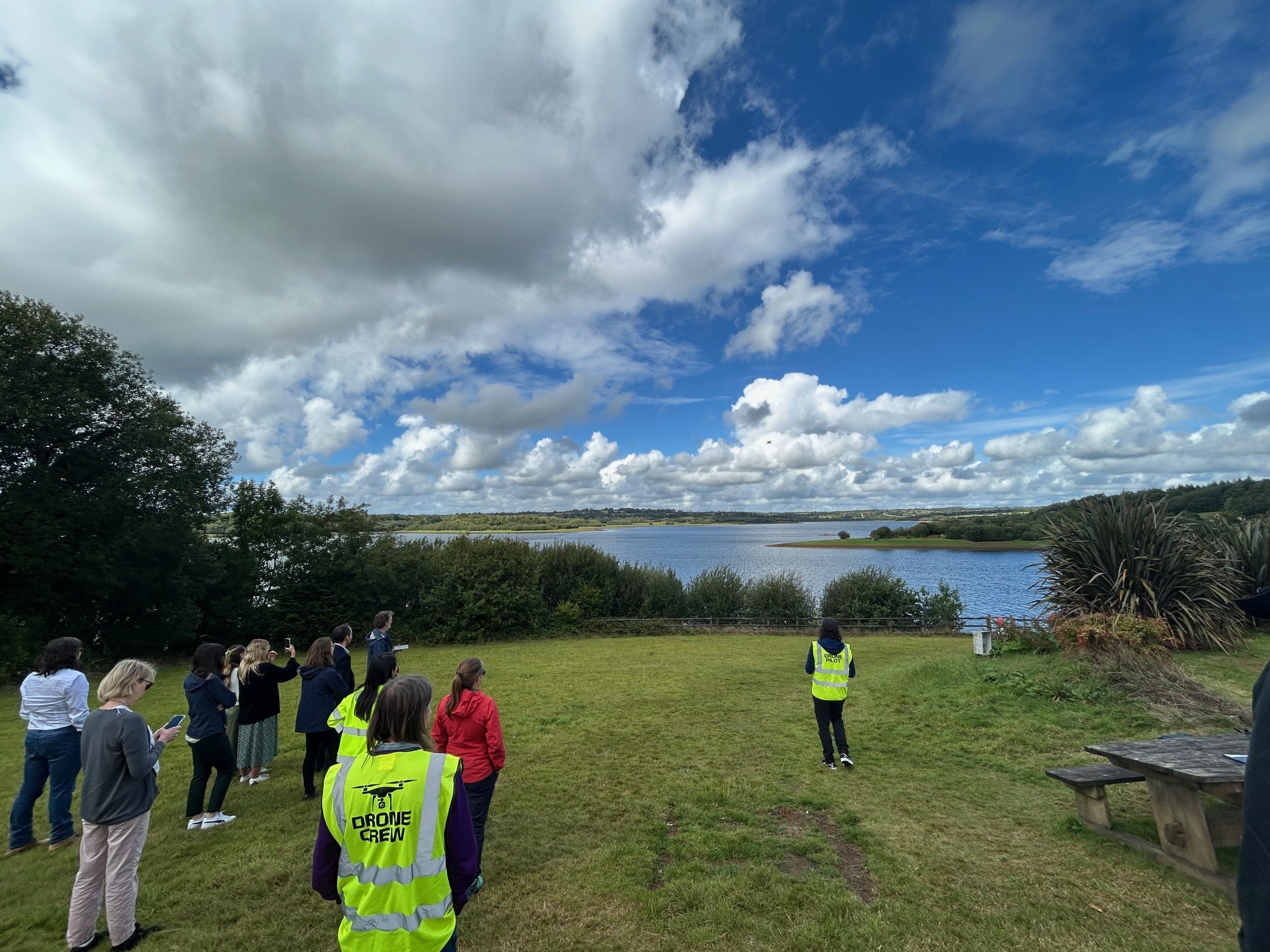 Officials in hi-vis testing a drone over a lake
