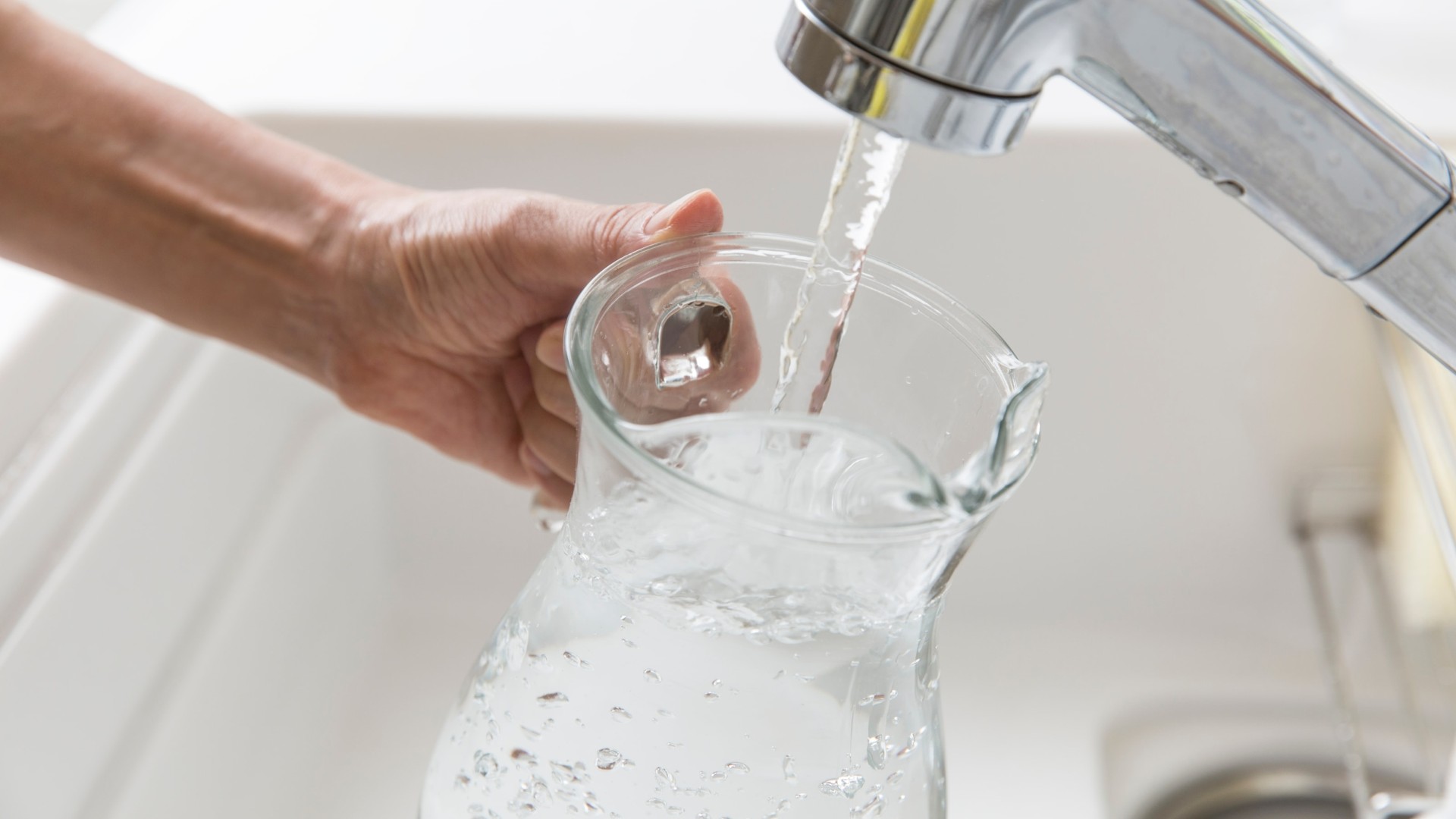 Glass jug filling up with tap water