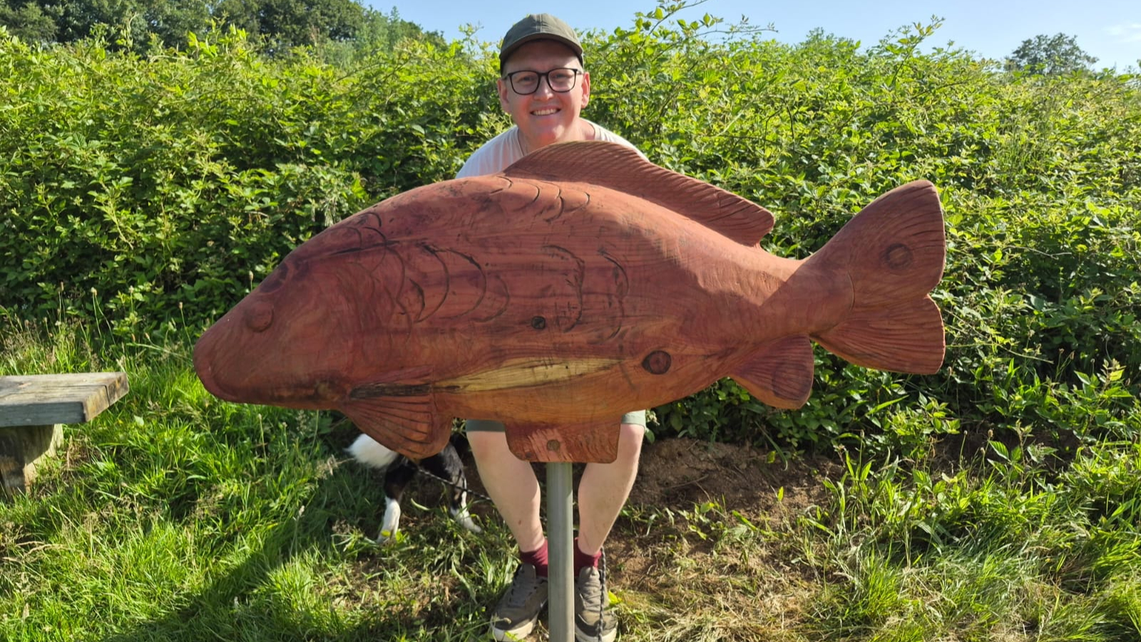 Man stood next to a large wooden model of a fish