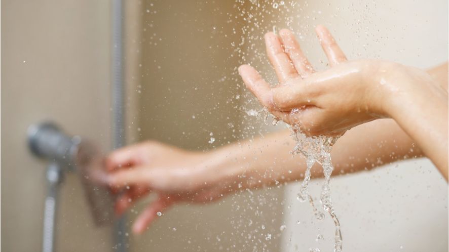 Two hands underneath a running shower