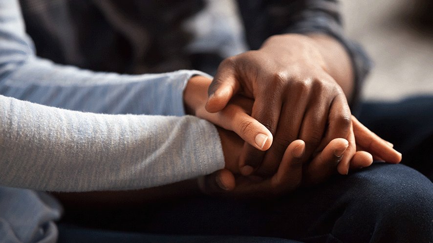 Two people holding hands in support 